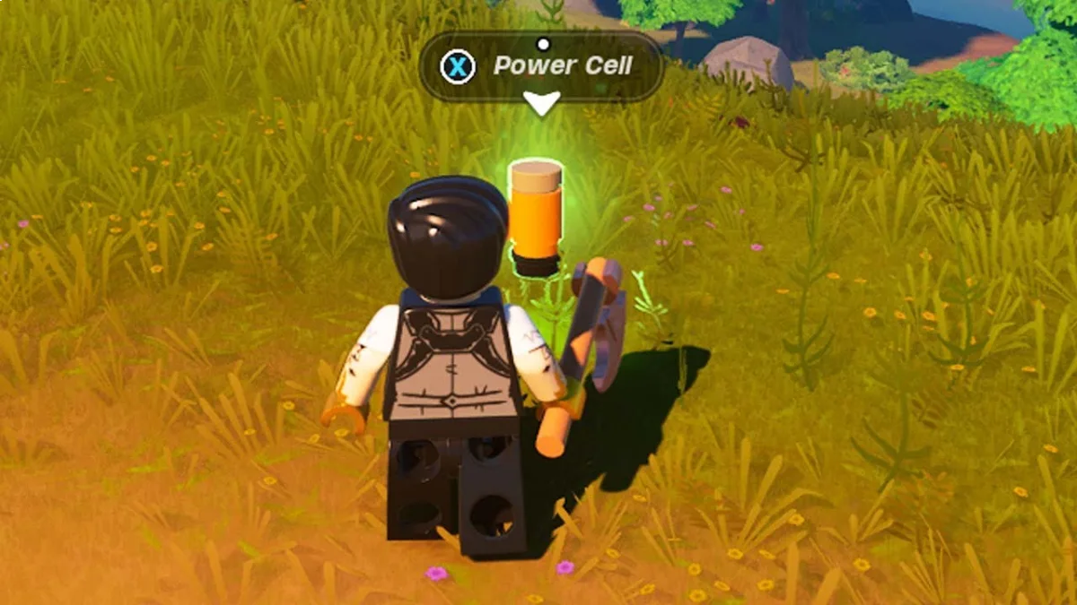 A Lego character stands in the grass, while a Fortnite player encounters a Power cell on the ground.